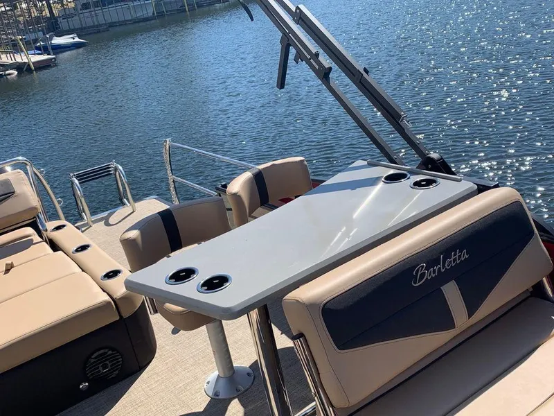 Slide: The Image of 2023 Barletta Cabrio 24UE pontoon boat with seating and table on a sunny lake. - 5