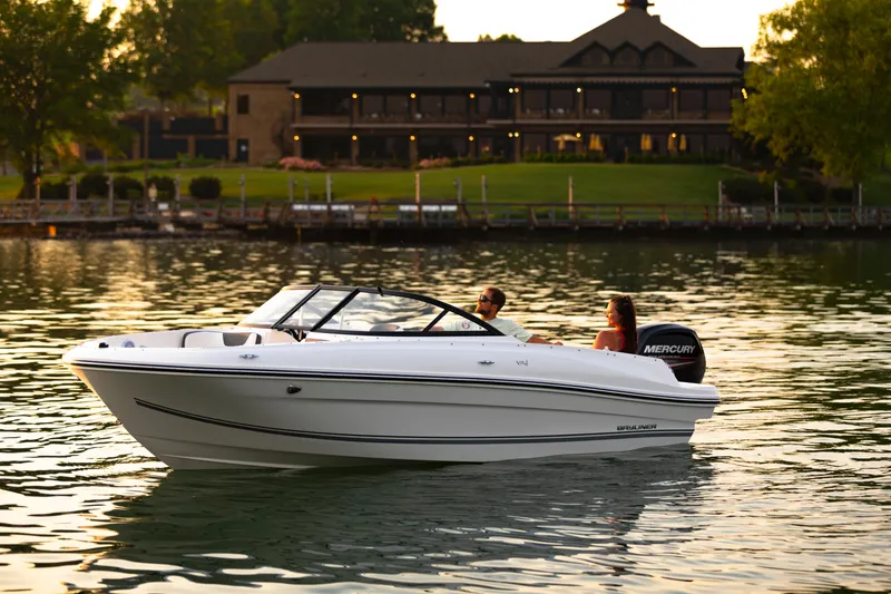 Slide: The Image of 2023 Bayliner VR4 OB boat cruising on a serene lake near a large house. - 3