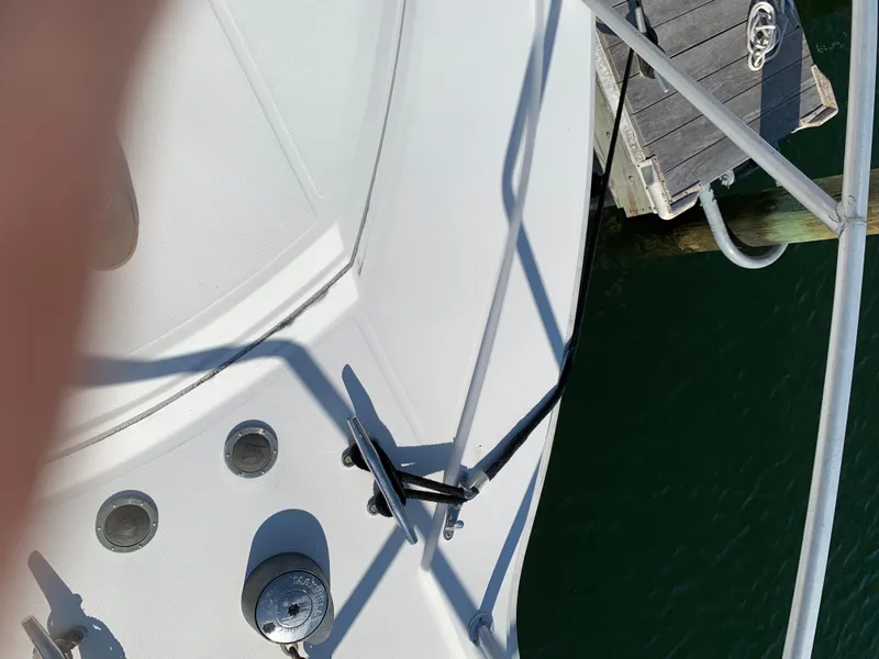 Slide: The Image of 1997 Phoenix 38 SFX Convertible boat deck near dock, showing railing and water. - 18