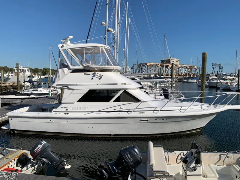 Slide: The Image of 1997 Phoenix 38 SFX Convertible yacht docked in a marina under clear blue skies. - 2