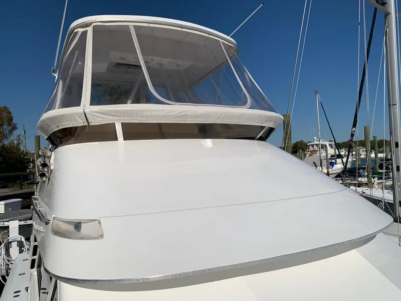 Slide: The Image of 1997 Phoenix 38 SFX Convertible yacht with clear canopy, docked under blue sky. - 25