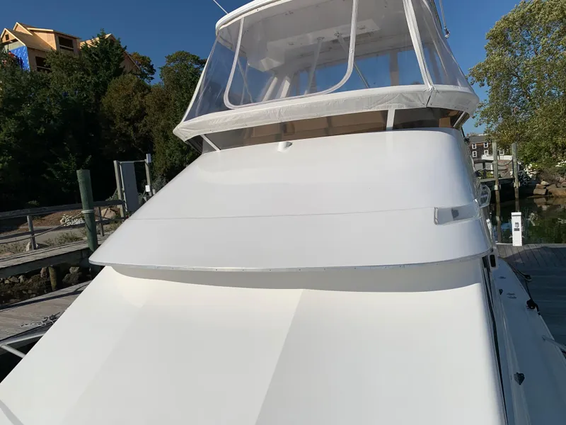 Slide: The Image of 1997 Phoenix 38 SFX Convertible boat docked, featuring sleek white design and clear enclosure. - 26