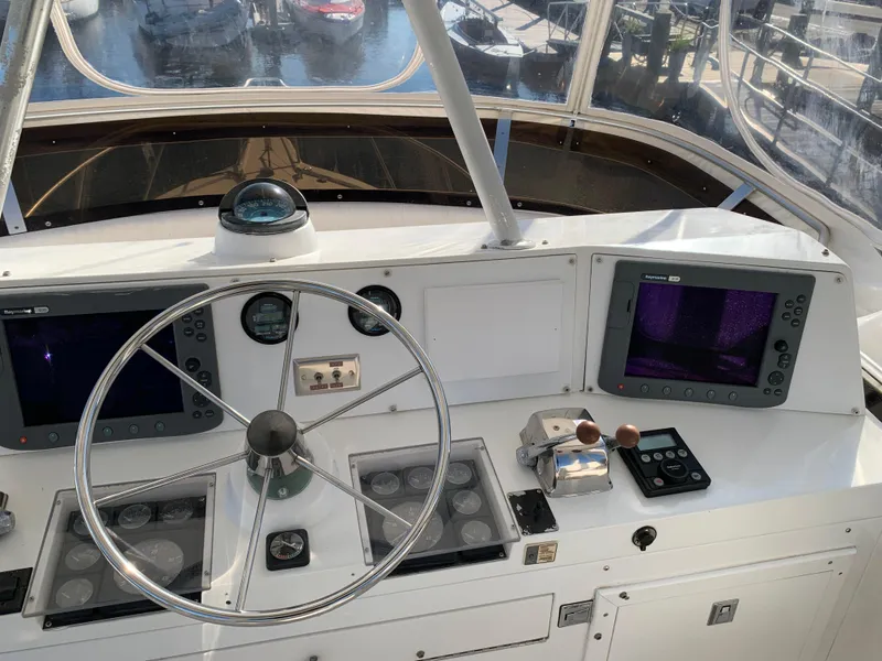Slide: The Image of Control panel of a 1997 Phoenix 38 SFX Convertible boat with steering wheel and navigation screens. - 31