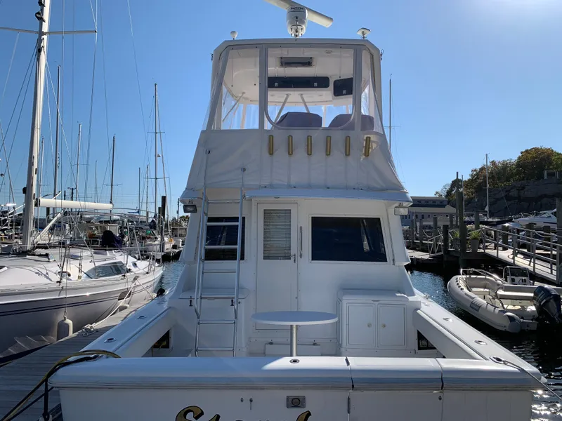 Slide: The Image of 1997 Phoenix 38 SFX Convertible yacht docked at marina under clear blue sky. - 7