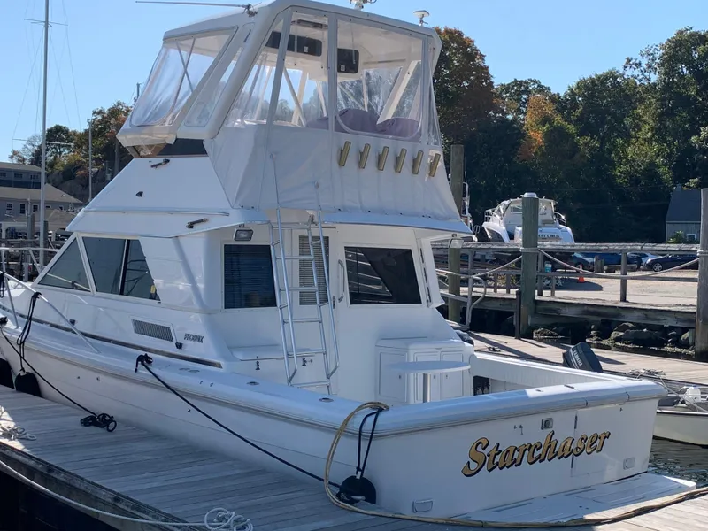 Slide: The Image of 1997 Phoenix 38 SFX Convertible yacht docked, named "Starchaser," with clear skies and trees in background. - 8
