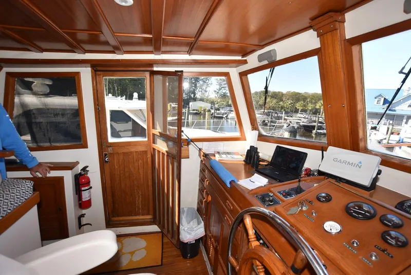Slide: The Image of 1983 Krogen Trawler helm with wooden interior, navigation equipment, and marina view. - 14