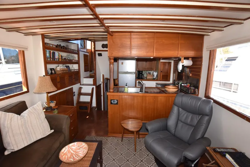 Slide: The Image of Interior of a 1983 Krogen Trawler featuring cozy seating, wooden cabinetry, and a compact kitchen area. - 18