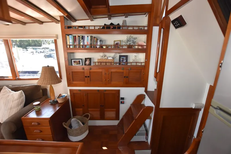 Slide: The Image of 1983 Krogen Trawler interior with wooden shelves, books, and cozy seating area. - 19
