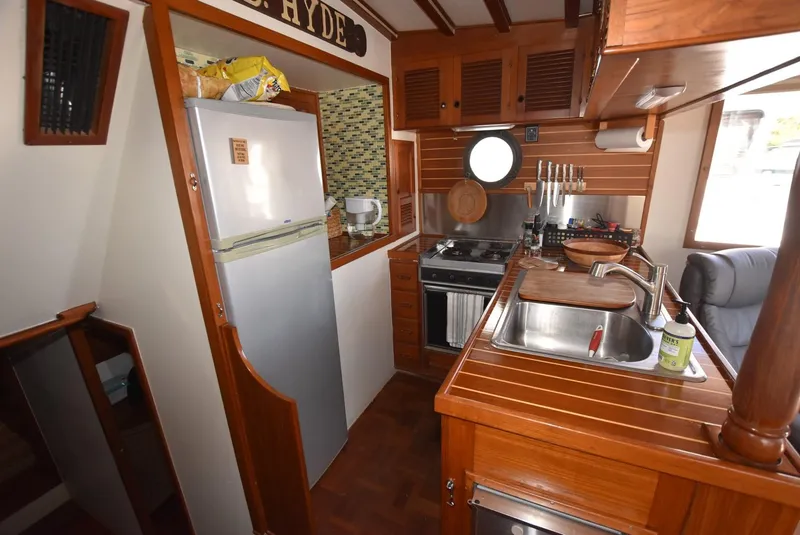 Slide: The Image of 1983 Krogen Trawler kitchen with wooden cabinetry, stove, sink, and refrigerator. Cozy maritime design. - 20