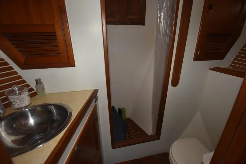 Slide: The Image of 1983 Krogen Trawler bathroom with wooden cabinets, stainless steel sink, and compact shower. - 25