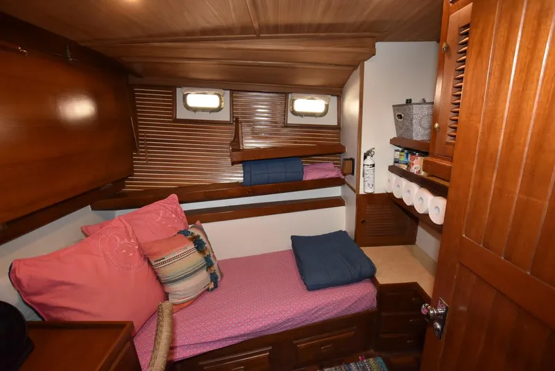 Slide: The Image of 1983 Krogen Trawler cabin with wooden interior, cozy bed, and storage shelves. - 26