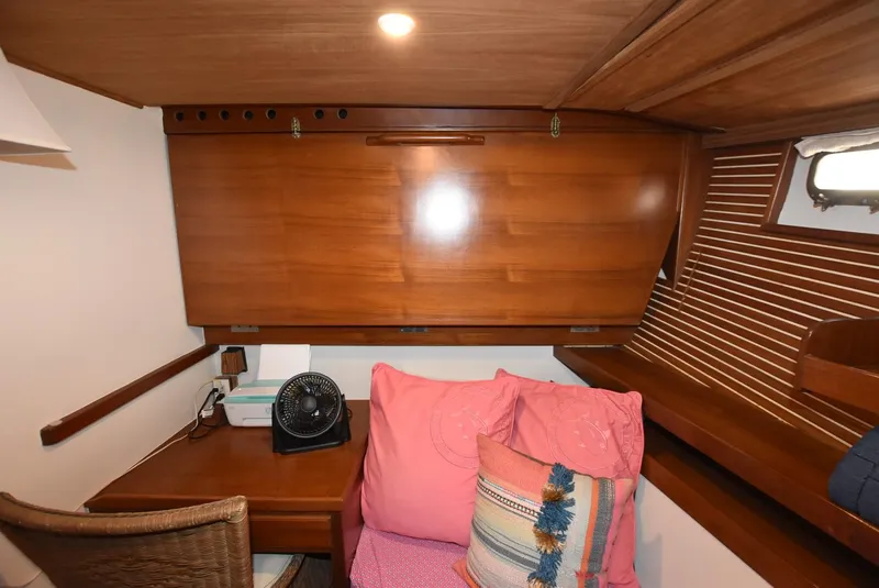 Slide: The Image of 1983 Krogen Trawler cabin with wooden interior, desk, and colorful cushions. - 27