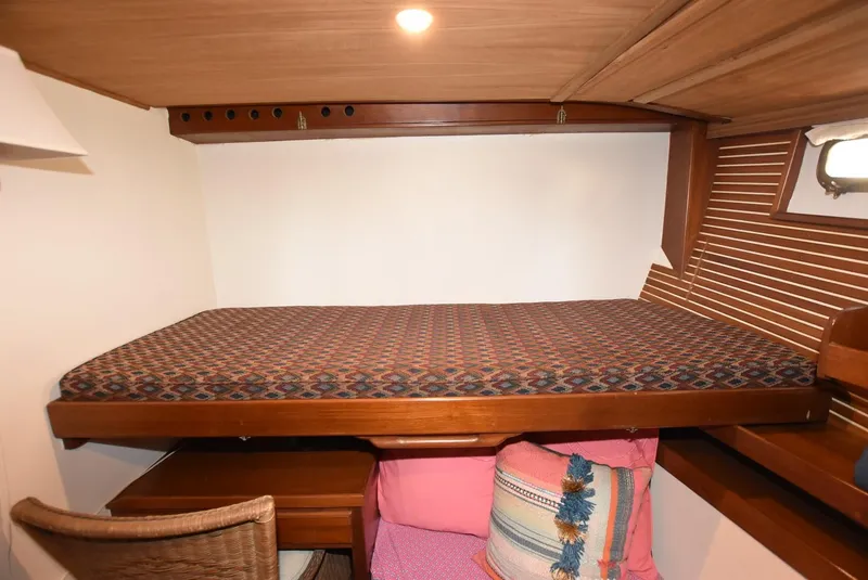Slide: The Image of 1983 Krogen Trawler cabin with cozy bed, wooden interior, and decorative pillows. - 28