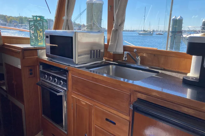Slide: The Image of Galley of 1983 Grand Banks 42 Classic with microwave, stove, and sink, overlooking marina. - 13