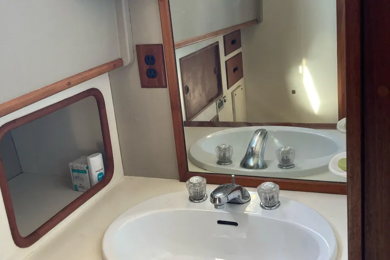 Slide: The Image of Bathroom sink area on a 1983 Grand Banks 42 Classic yacht, featuring a mirror and storage. - 17