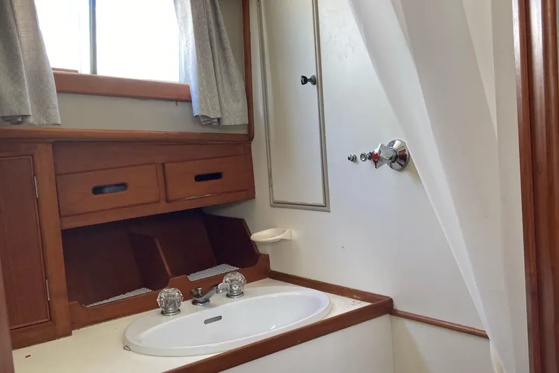 Slide: The Image of 1983 Grand Banks 42 Classic yacht bathroom with sink, wooden cabinetry, and window. - 19
