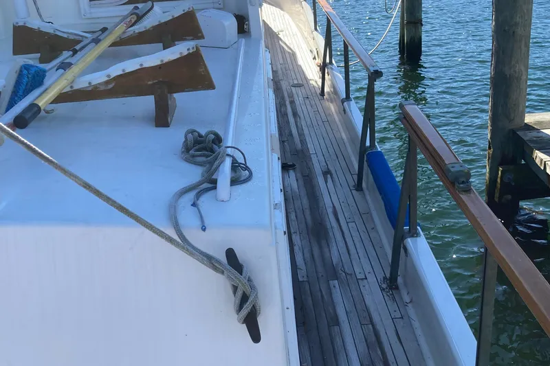 Slide: The Image of 1983 Grand Banks 42 Classic yacht deck with wooden railings and mooring ropes. - 4