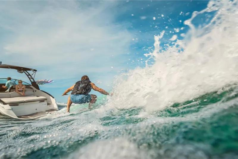 Slide: The Image of 2023 Sea Ray SLX 260 Surf boat with a surfer riding waves. - 12
