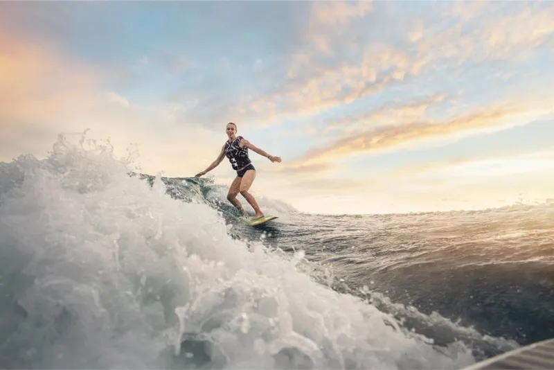 Slide: The Image of Person surfing behind a 2023 Sea Ray SLX 260 Surf boat at sunset. - 16