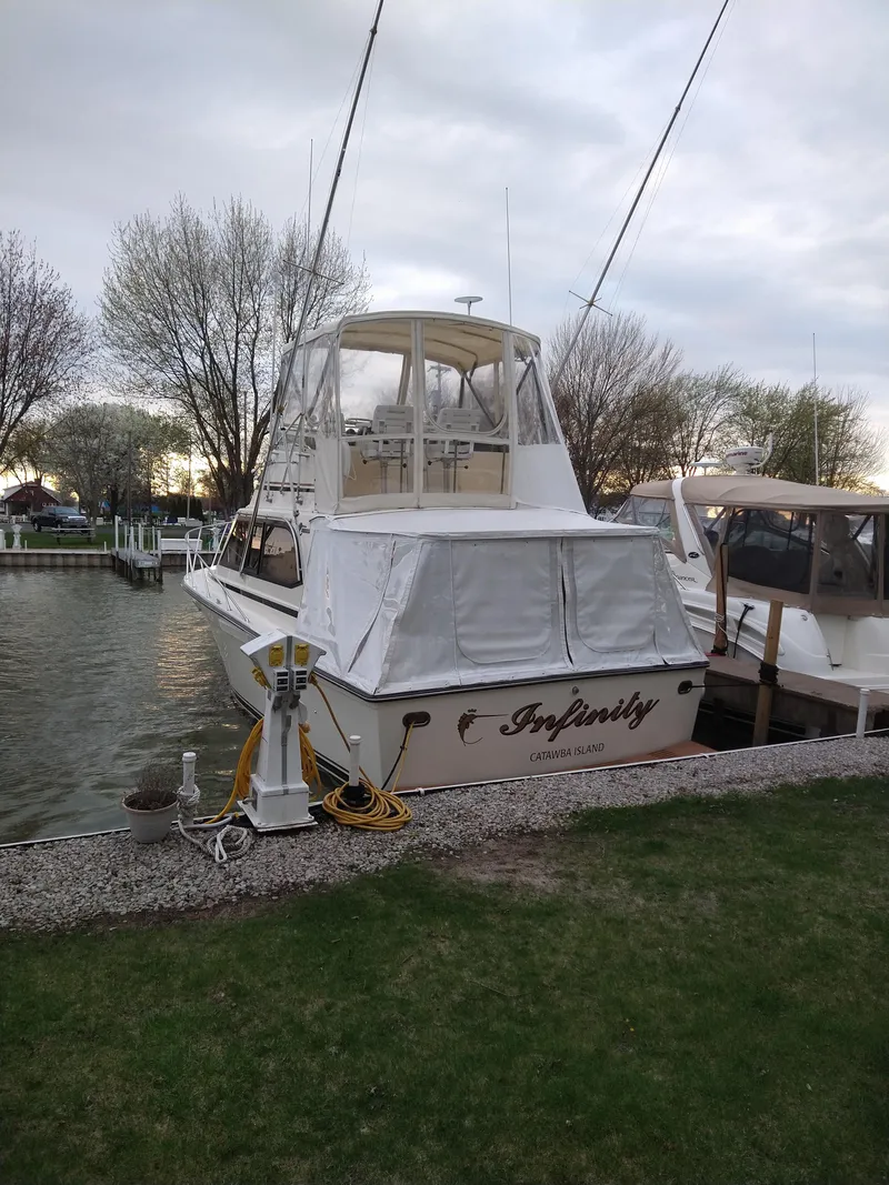 Slide: The Image of 1989 Egg Harbor 33 Sedan boat docked by a grassy shore, overcast sky. - 14