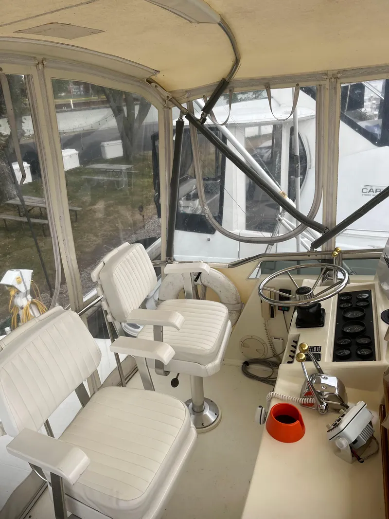 Slide: The Image of 1989 Egg Harbor 33 Sedan boat interior with helm, steering wheel, and two white captain chairs. - 6