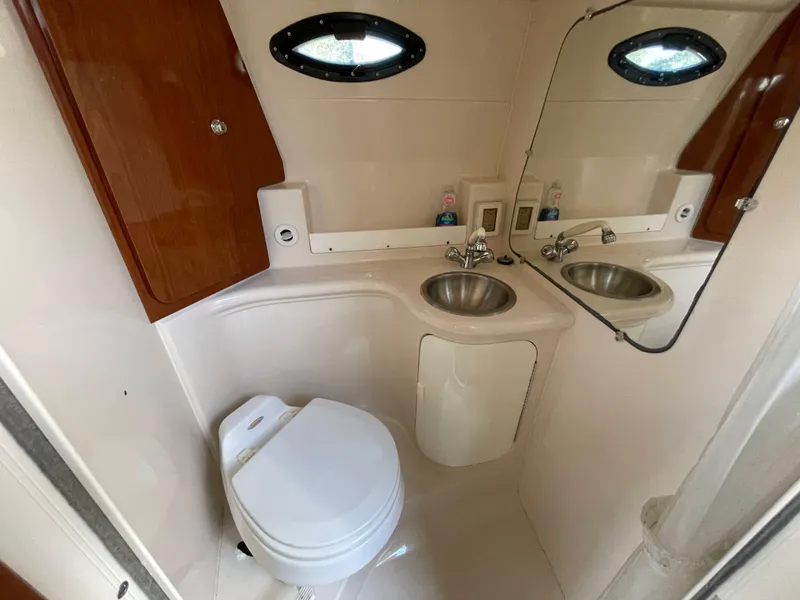 Slide: The Image of 2006 Regal 2665 Commodore boat bathroom with toilet, sink, mirror, and storage cabinet. - 22