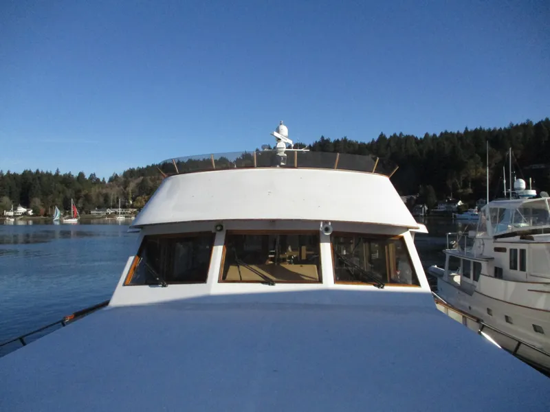 Slide: The Image of 1984 McQueen Flush Deck Motoryacht on calm water, surrounded by forested shoreline. - 10