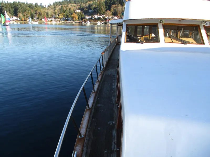 Slide: The Image of 1984 McQueen Flush Deck Motoryacht on serene water with scenic background. - 12