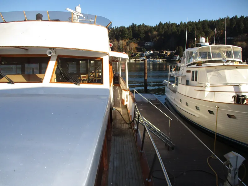 Slide: The Image of 1984 McQueen Flush Deck Motoryacht docked beside another yacht, scenic waterfront view. - 13
