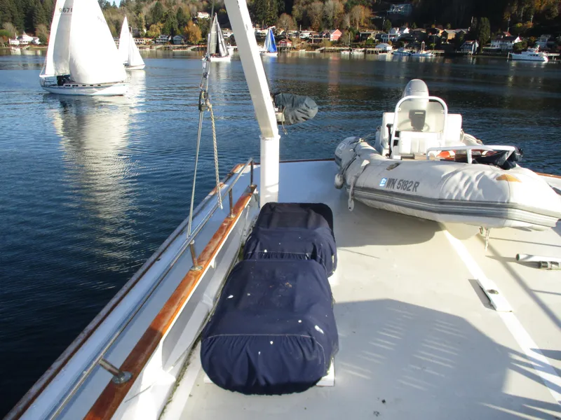 Slide: The Image of 1984 McQueen Flush Deck Motoryacht deck with dinghy, overlooking calm waters and sailboats. - 20