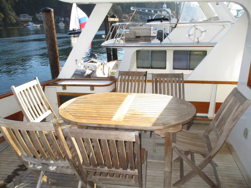 Slide: The Image of 1984 McQueen Flush Deck Motoryacht with wooden deck furniture, docked by calm waters. - 24