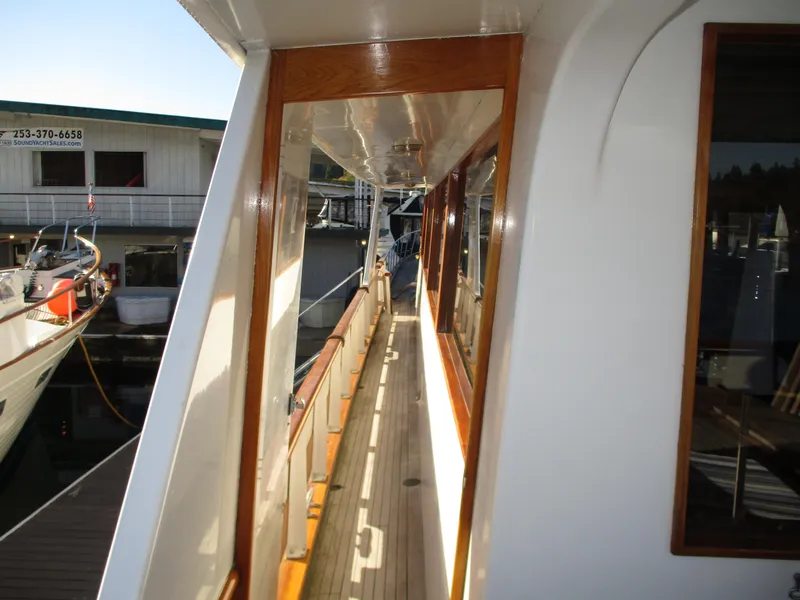 Slide: The Image of 1984 McQueen Flush Deck Motoryacht side deck with wooden trim and marina view. - 28