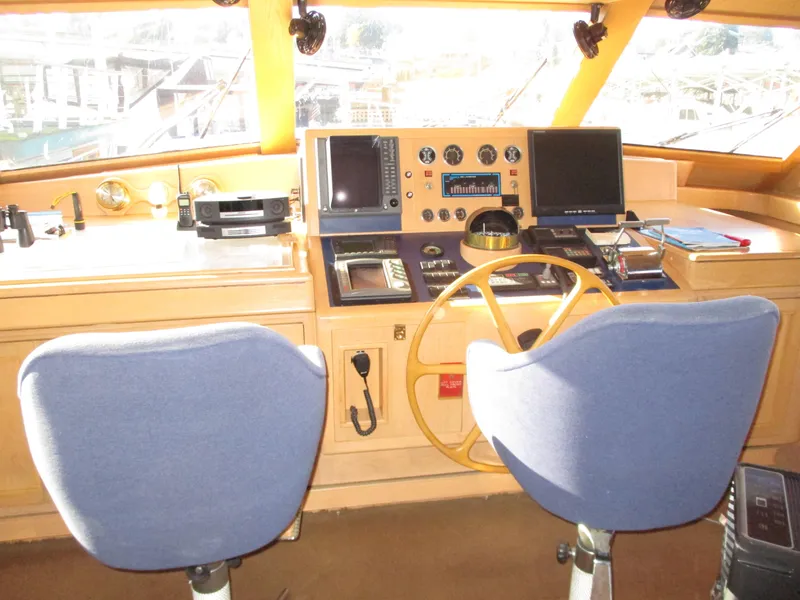 Slide: The Image of 1984 McQueen Flush Deck Motoryacht helm with dual blue chairs and navigation equipment. - 30