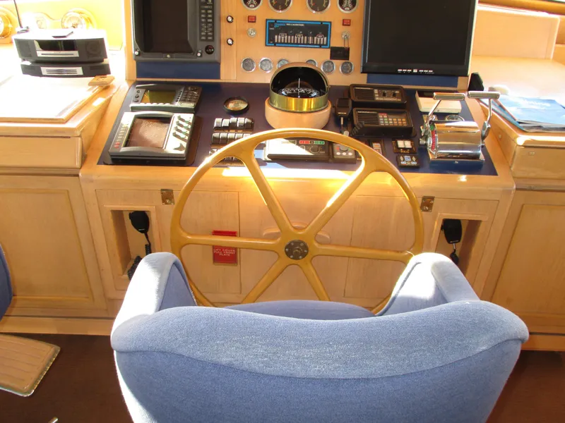 Slide: The Image of 1984 McQueen Flush Deck Motoryacht helm with wooden wheel and navigation instruments. - 32