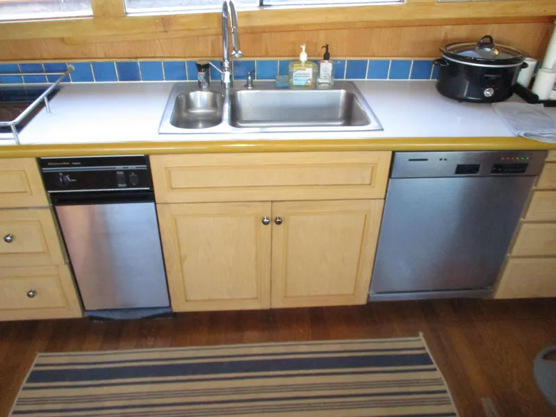 Slide: The Image of Kitchen area on 1984 McQueen Flush Deck Motoryacht with sink, dishwasher, and wooden cabinets. - 49