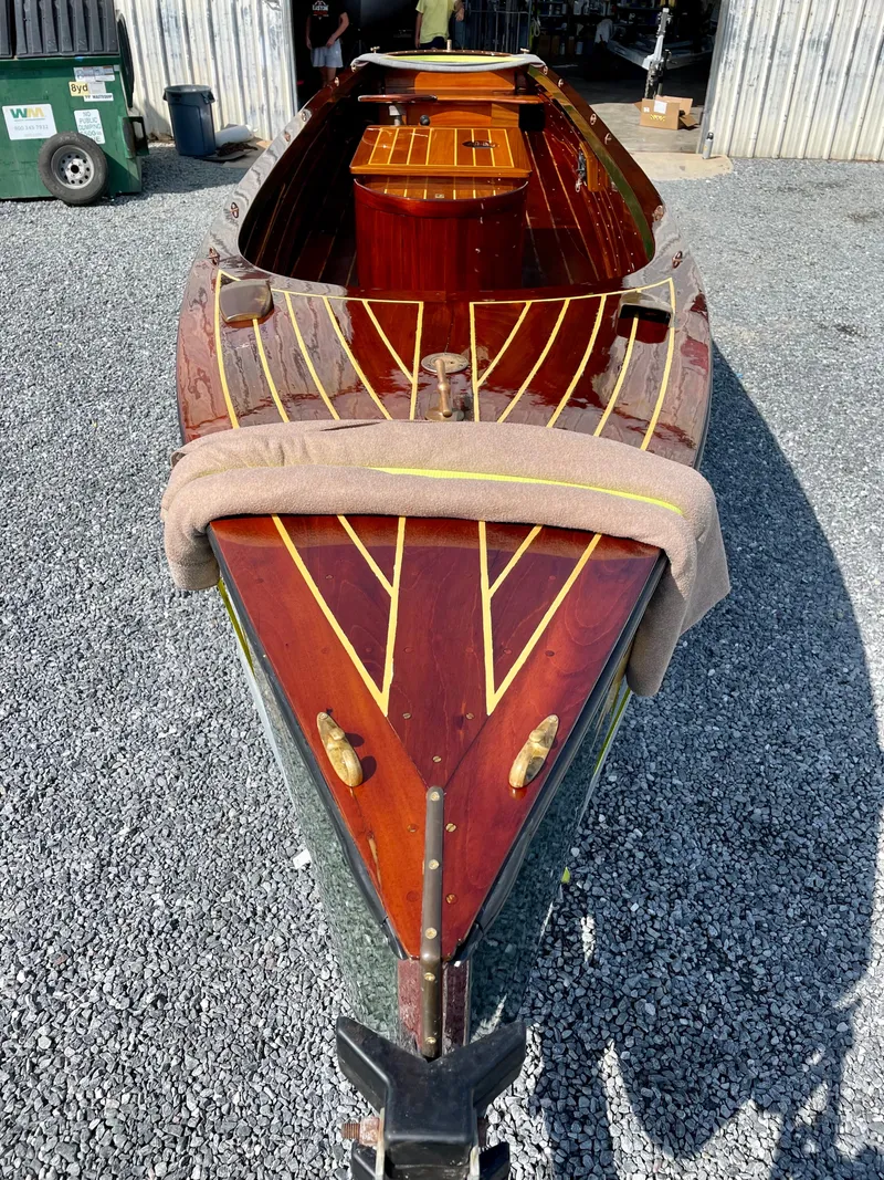 Slide: The Image of Custom 1990 29 Launch boat with wooden deck and intricate design, parked on gravel. - 19