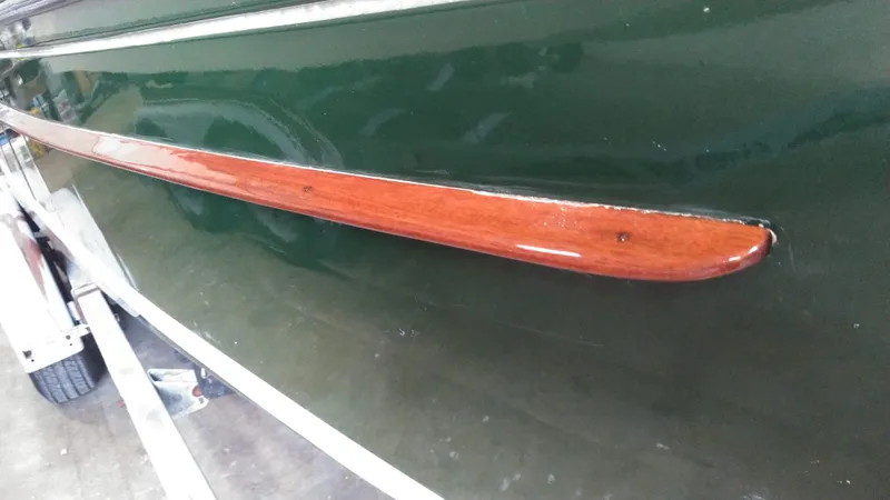 Slide: The Image of Close-up of a 1990 Custom 29 Launch boat with green hull and wooden trim. - 6