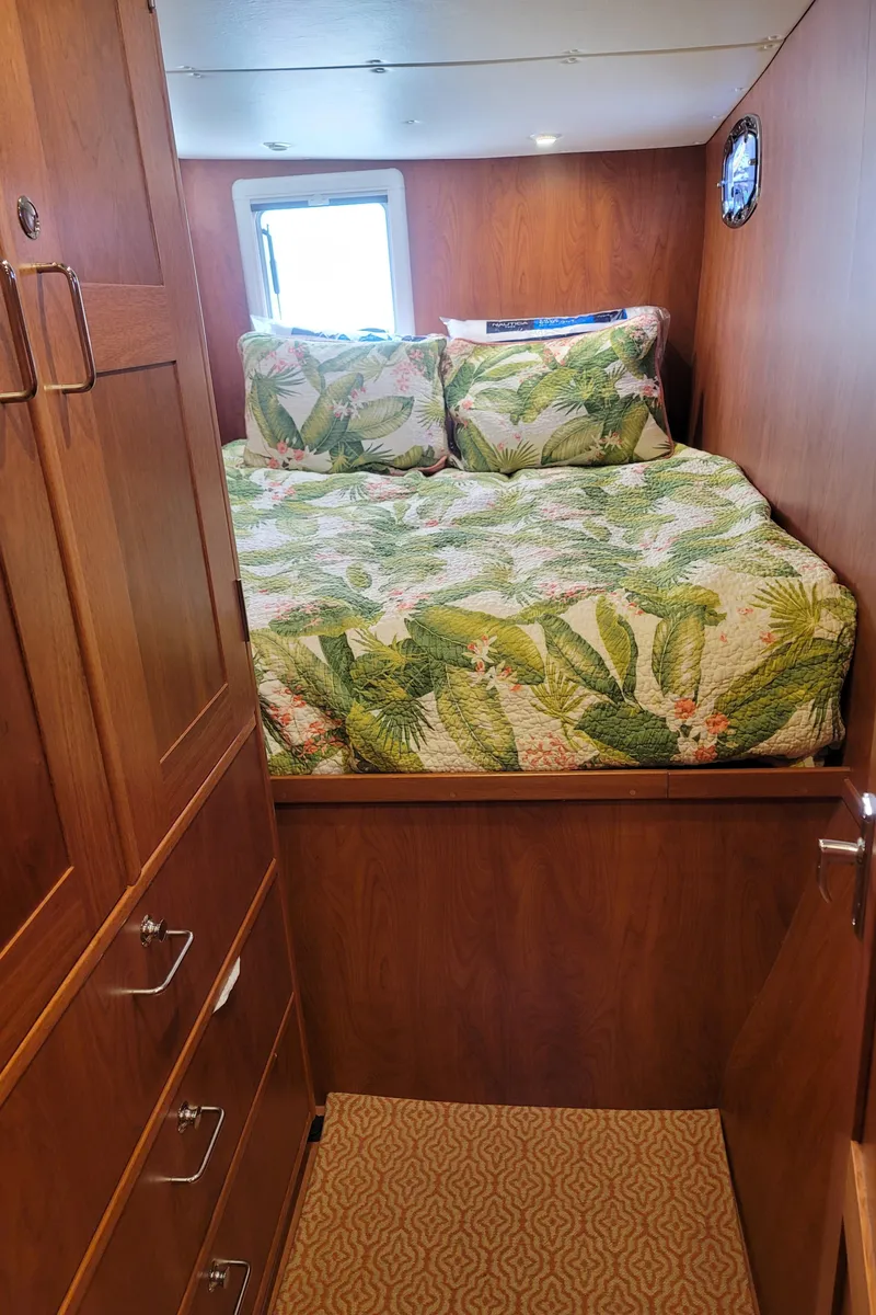 Slide: The Image of 2019 Endeavour Catamaran 440 HYBRID bedroom with tropical-themed bedding and wooden cabinetry. - 4