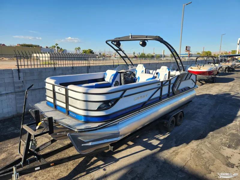 Slide: The Image of 2023 Crest Caribbean RS 250 SLS pontoon boat on trailer, parked outdoors. - 1