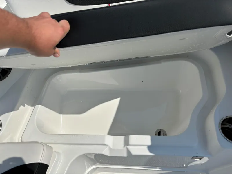 Slide: The Image of Open storage compartment in 2023 Tahoe 1950 boat, with hand lifting seat cushion. - 18