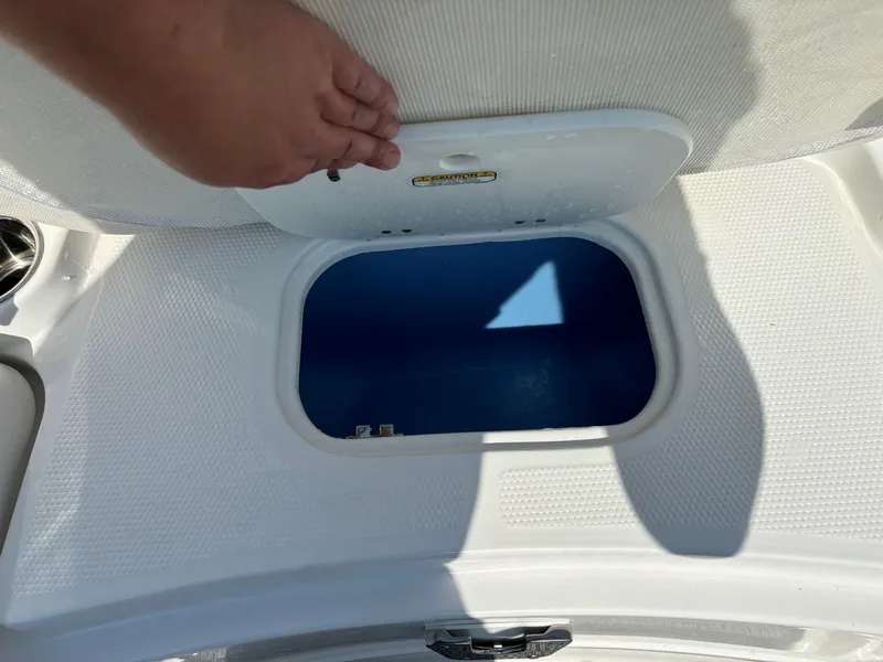 Slide: The Image of Boat storage compartment in a 2023 Tahoe 1950 model, open with hand lifting lid. - 21