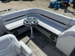 Slide: The Image of 2023 Sweetwater 2086C pontoon boat interior with gray seating and a round table. - 2