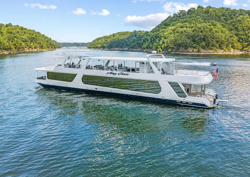 The Image of 2009 Sumerset 23' x 118' houseboat cruising on a scenic lake with lush green hills. - 0