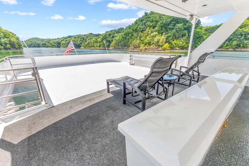 Slide: The Image of Luxurious 2009 Sumerset houseboat deck with lounge chairs, scenic lake view, and American flag. - 24