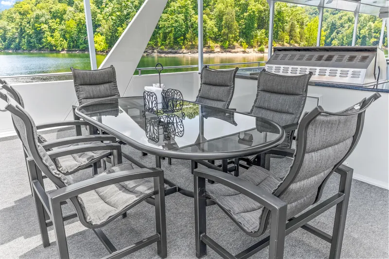 Slide: The Image of Outdoor dining area on 2009 Sumerset houseboat, featuring glass table and cushioned chairs. - 33