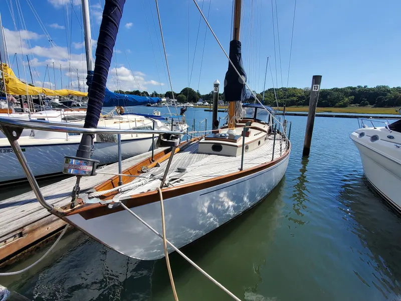 Slide: The Image of 1958 Custom Larson 40 sailboat docked in a sunny marina, surrounded by other boats. - 1