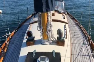 Slide: The Image of 1958 Custom Larson 40 sailboat deck with mast and rigging, on calm water. - 16