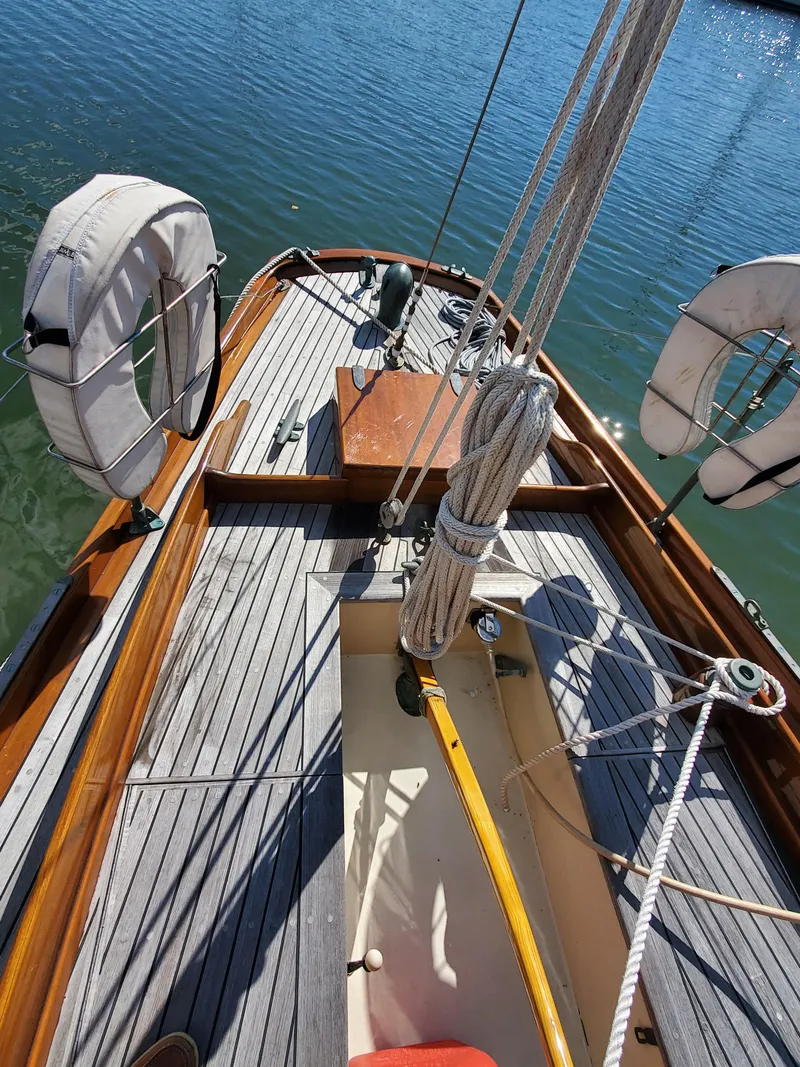 Slide: The Image of 1958 Custom Larson 40 sailboat deck with lifebuoys and wooden details on calm water. - 9
