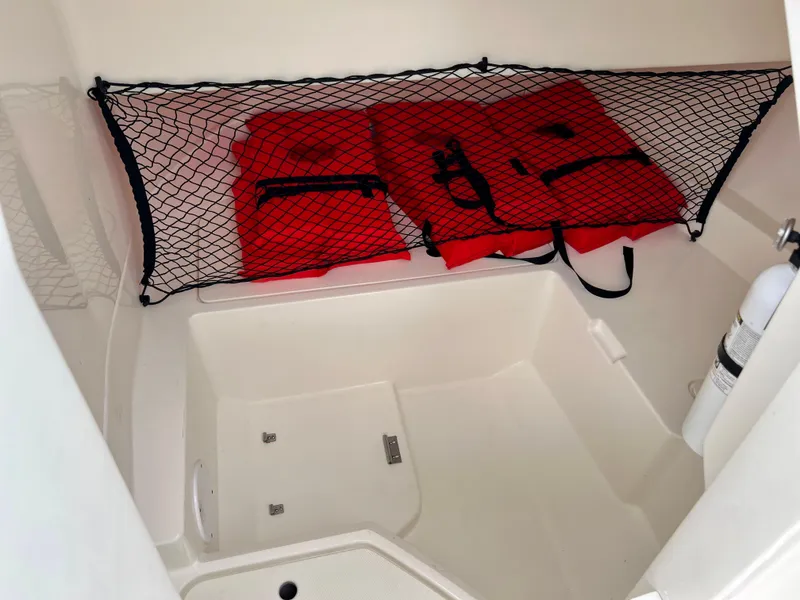 Slide: The Image of 2020 Sea Ray SDX 250 storage compartment with life jackets and safety equipment. - 28