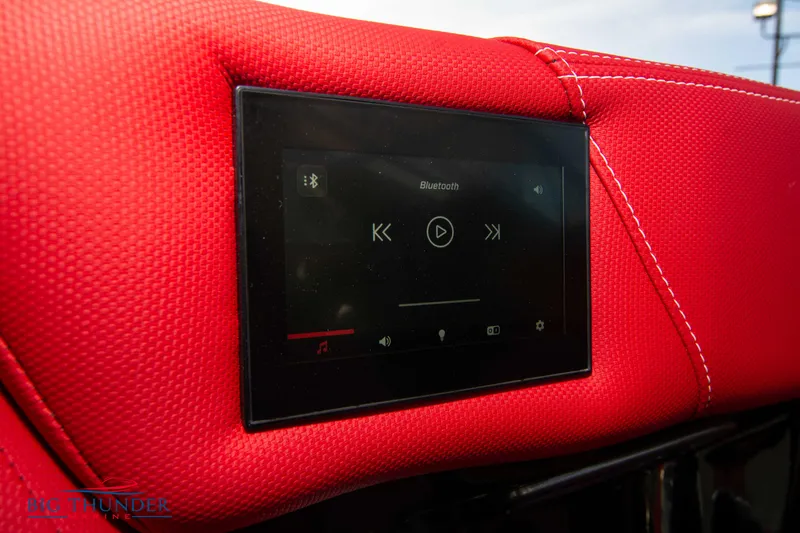 Slide: The Image of 2021 MasterCraft X24 boat touchscreen control panel on red upholstery. - 37